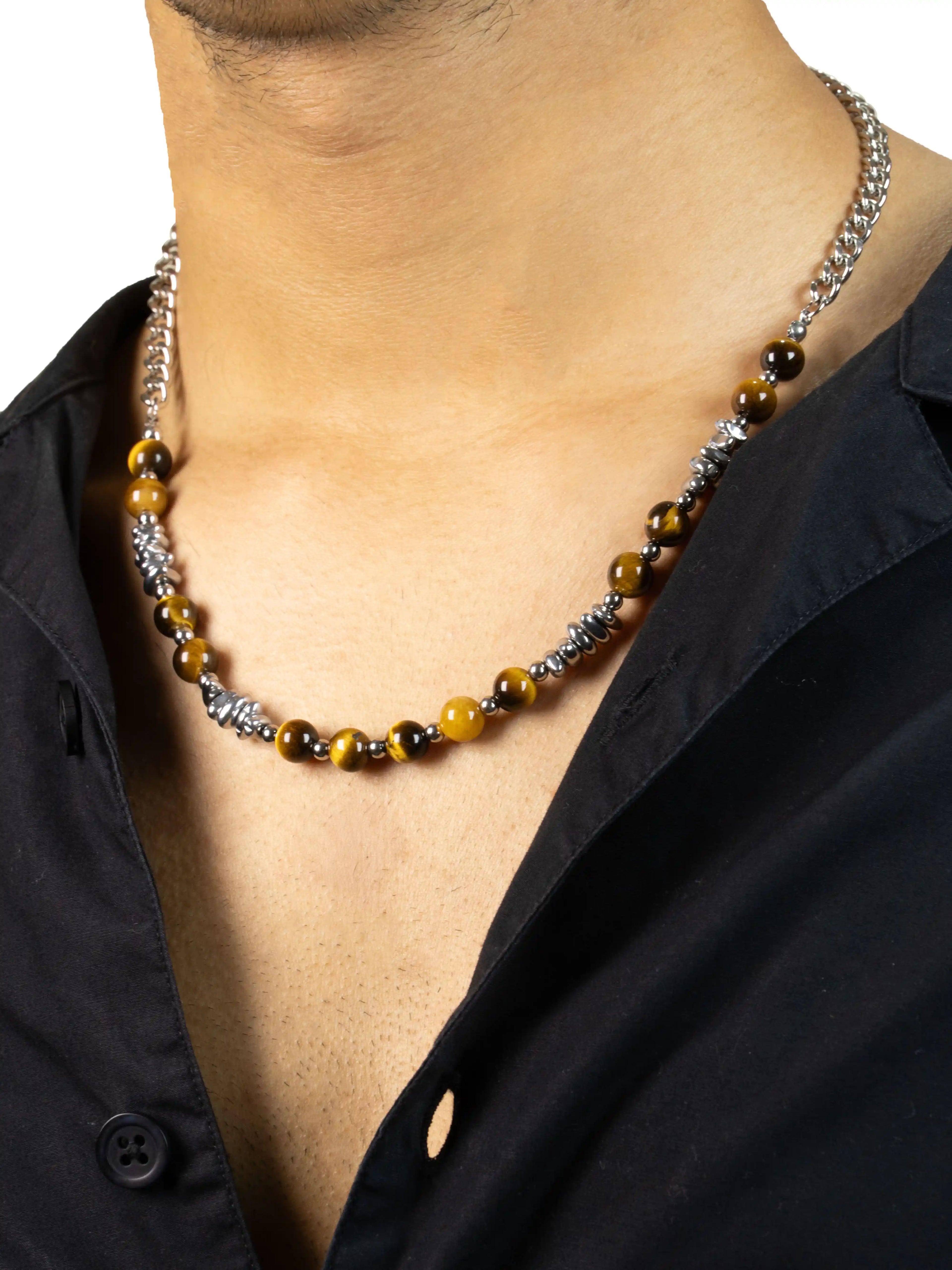 Necklace with brown and silver beads worn by a person wearing a black shirt.
stawp