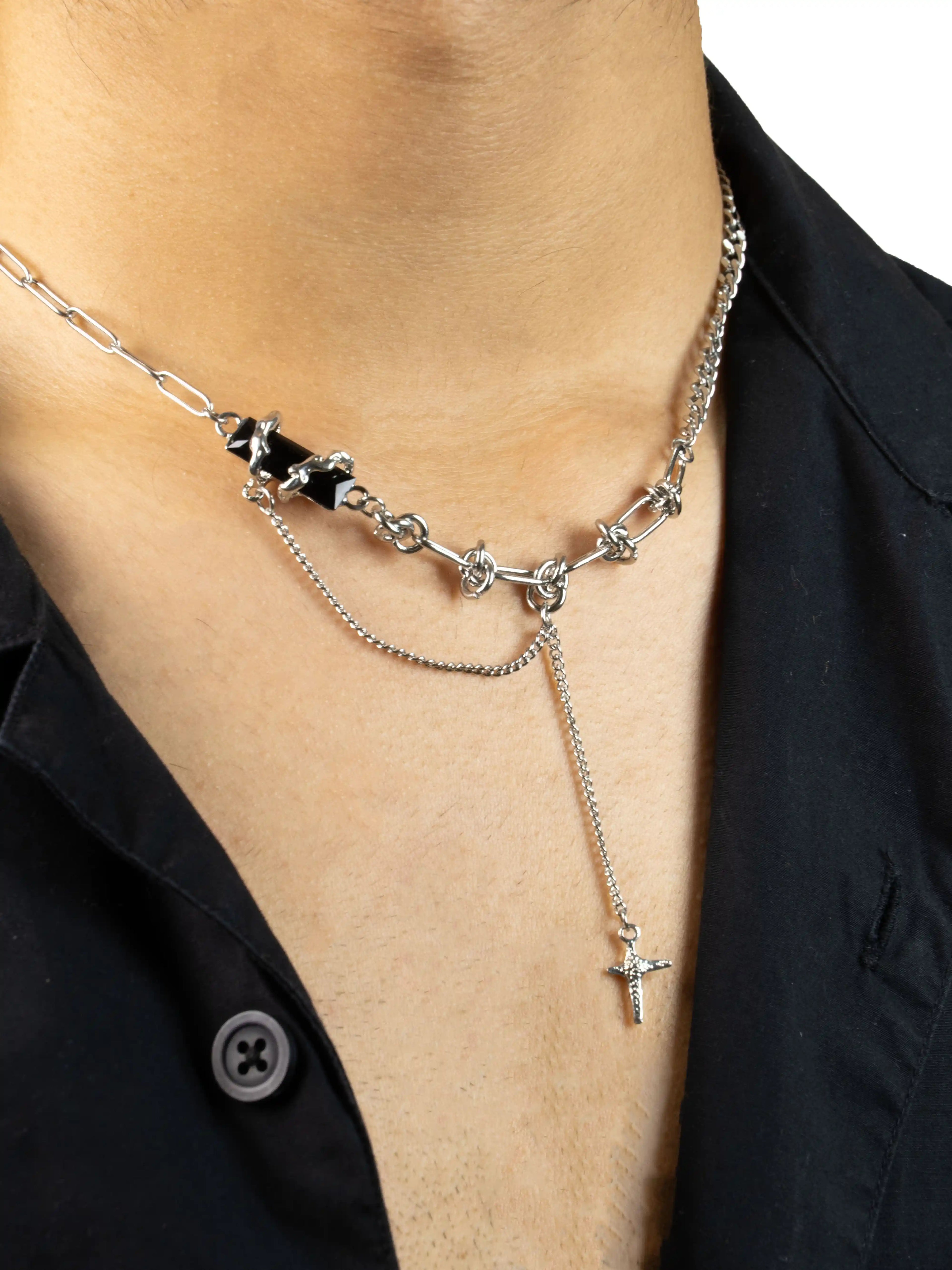 Necklace with black beads and silver chain on a person wearing a black shirt.
stawp