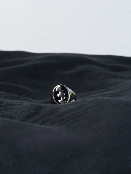 Silver ring with batman logo on a textured black fabric background