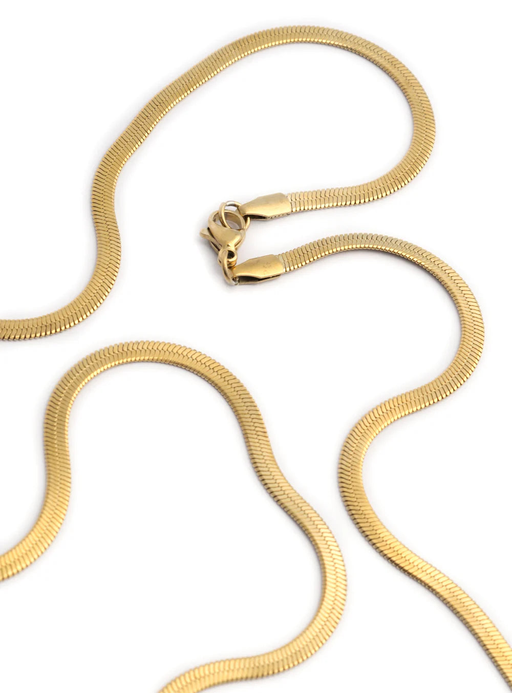 Close-up view of the Golden Foxtail chain necklace by Stawp, focusing on the intricate texture and elegant curves of the chain as it forms loose waves on a white background.