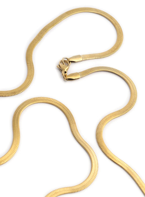 Close-up view of the Golden Foxtail chain necklace by Stawp, focusing on the intricate texture and elegant curves of the chain as it forms loose waves on a white background.